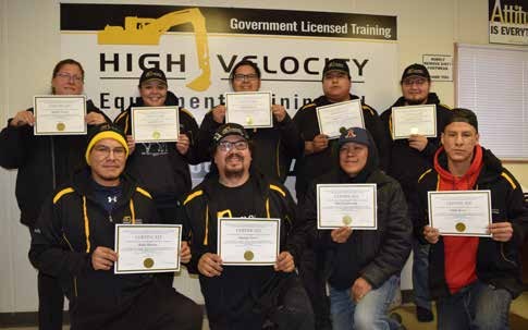 Nine graduates holding framed certificates, standing in two rows beneath a banner reading High Velocity Equipment Training, Government Licensed Training.