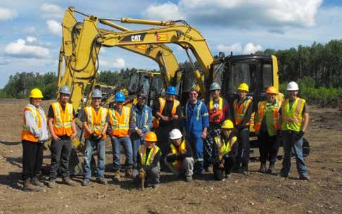 A crew of about twelve standing on a cleared and levelled site between two tracked excavators.